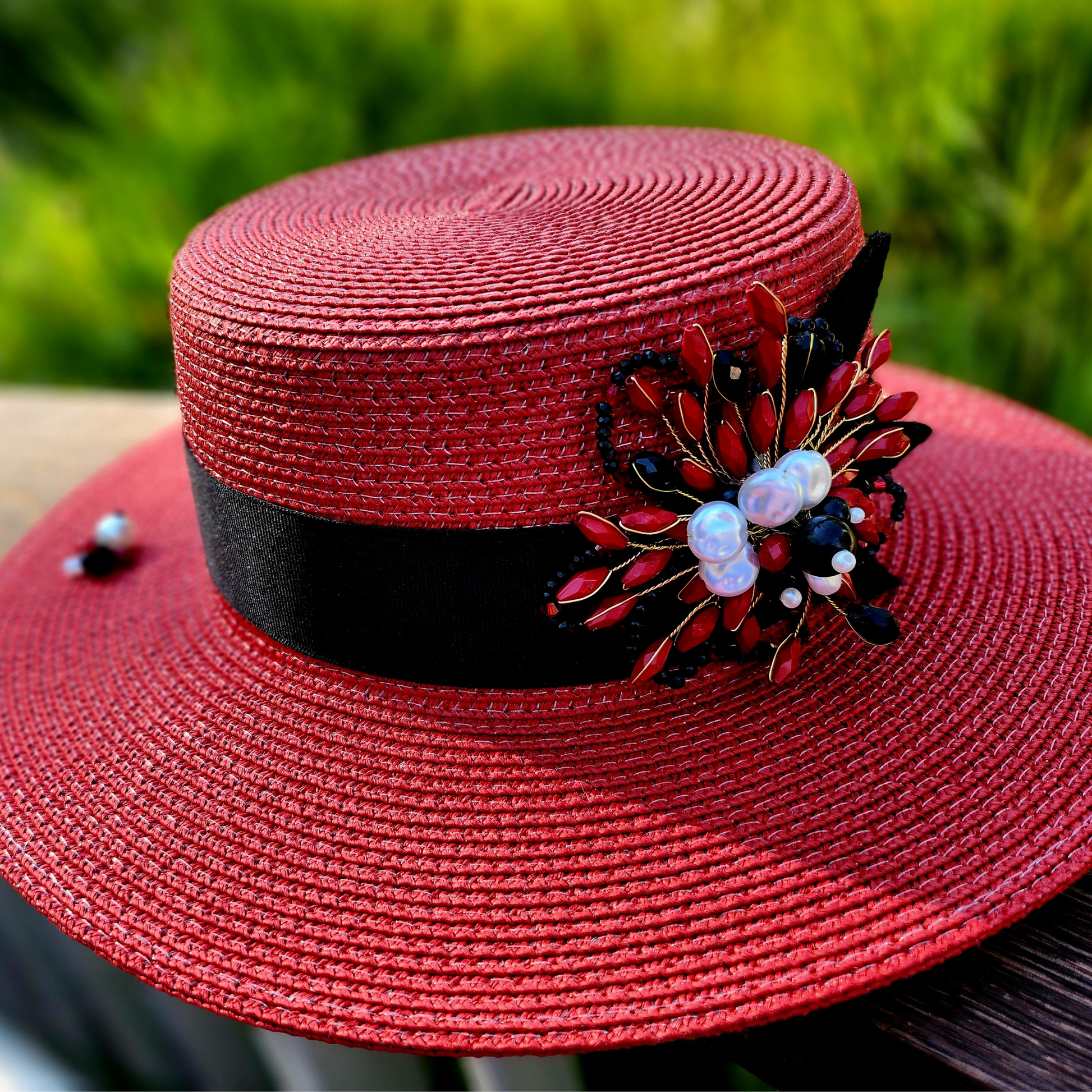 Red Straw Boater Hat with Brooch-a photo of the hat in the foreground close up